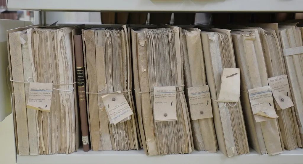 Shelves of old paper files bundled, tagged and bulging out of order